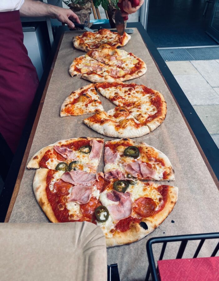 Verschiedene frisch gebackene Steinofenpizzen werden für die Gäste aufgeschnitten