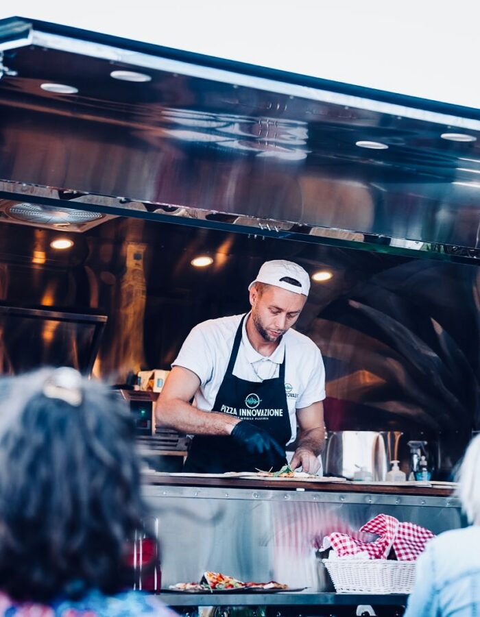 Pizzabäcker bereitet im Airstream-Foodtruck frische Pizza vor Gästen zu