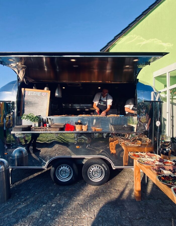 Mobiler Pizza-Airstream mit frisch zubereiteten Pizzen und Buffet bei einer Veranstaltung